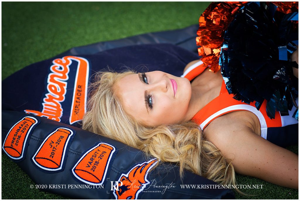 Picture of High school senior cheerleader laying on her letterman jacket