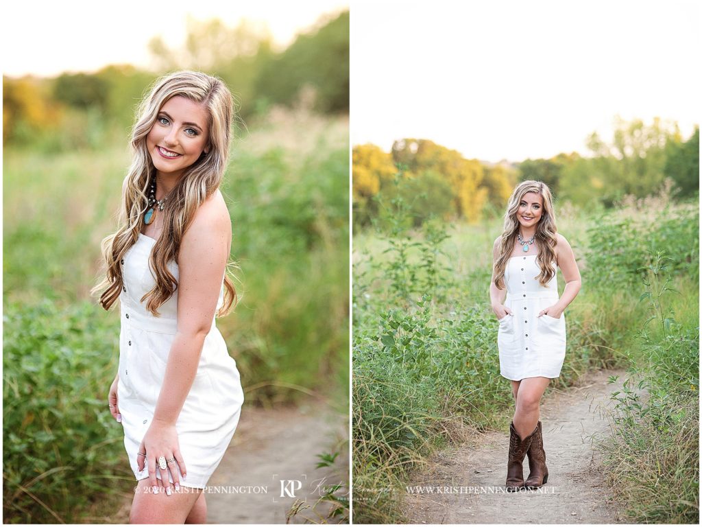 senior girl in white dress and cowboy boots standing in nature field