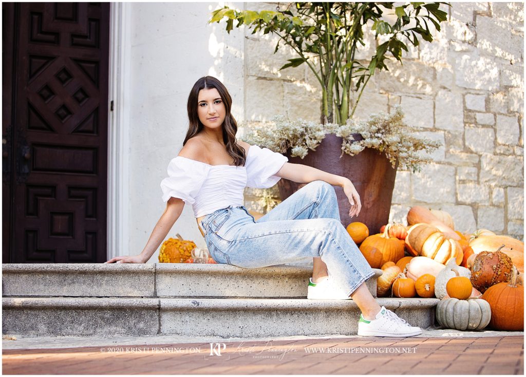 senior girl sitting pose on steps at the Dallas Arboretum with pumpkins